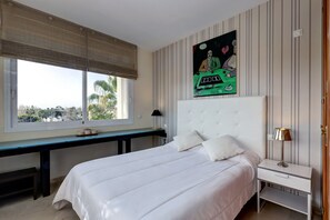 Un dormitorio con cama, mesita de noche, lámpara y ventana con persianas.