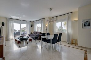 Una sala de estar moderna con comedor, ventanas amplias y vistas a la ciudad.