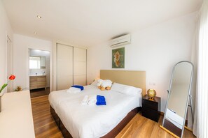 A hotel room with a bed, a bedside table, a mirror, and a wall-mounted air conditioner.
