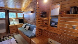 Un acogedor interior de cabaña con detalles de madera, un sofá, una mesa de centro y un escritorio con una lámpara.