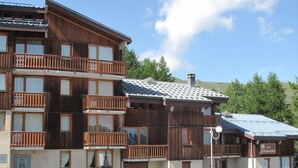 Un edificio de madera de varios pisos con balcones, un cimiento de piedra y un letrero que dice 