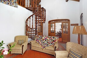 Ein Wohnzimmer mit einer Holztreppe, einem gemusterten Sofa und einem Wandbild.