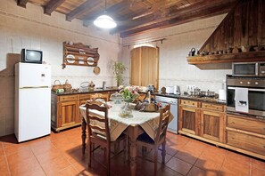 Eine Küche mit Holzausstattung, einem Esstisch mit Stühlen, einem Kühlschrank, einer Mikrowelle und einem Herd.