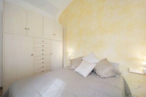 A bedroom with a bed, a wardrobe, and a nightstand with a lamp.