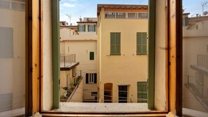 A view through a window of a building with multiple balconies, a courtyard, and neighboring buildings.