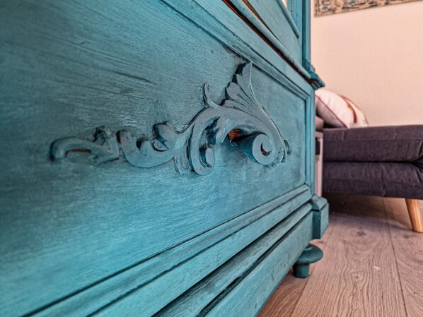 Une commode de couleur turquoise, ornée de sculptures complexes, et un plancher en bois.
