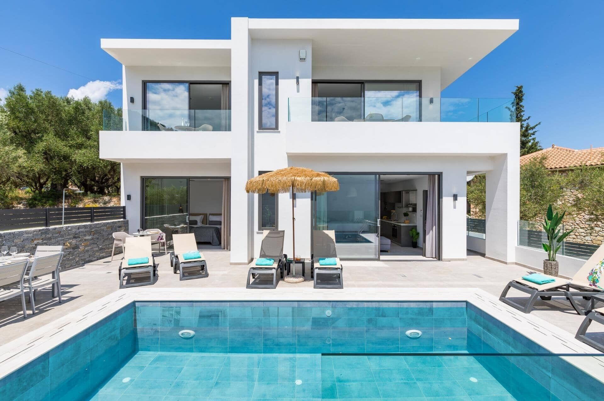 Ein modernes, zweistöckiges Haus mit Swimmingpool, Gartenmöbeln und einem Strohdachschirm.
