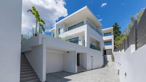 Una moderna casa a due piani con una scala che conduce a un balcone in vetro.
