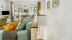 Ein modernes Wohnzimmer mit Sofa, Fernseher und Essbereich.