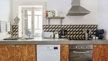 Una cocina equipada con lavavajillas, horno, tostadora, hervidor y cafetera.