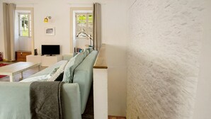 Una sala de estar moderna con un sofá, un televisor de pantalla plana, un banco de madera y una escalera.