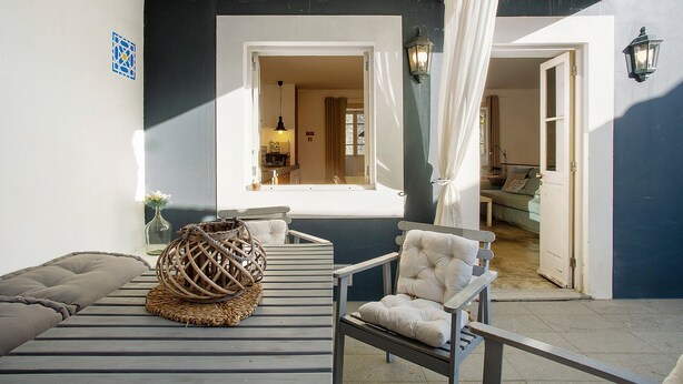 Una habitación con una cama, una silla, una cesta de mimbre y un aplique colgante.
