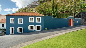 Un edificio de dos pisos con techo de tejas rojas, fachada azul y puerta roja.
