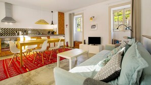 Una sala de estar moderna con un sofá, un televisor y un comedor con sillas y una mesa.