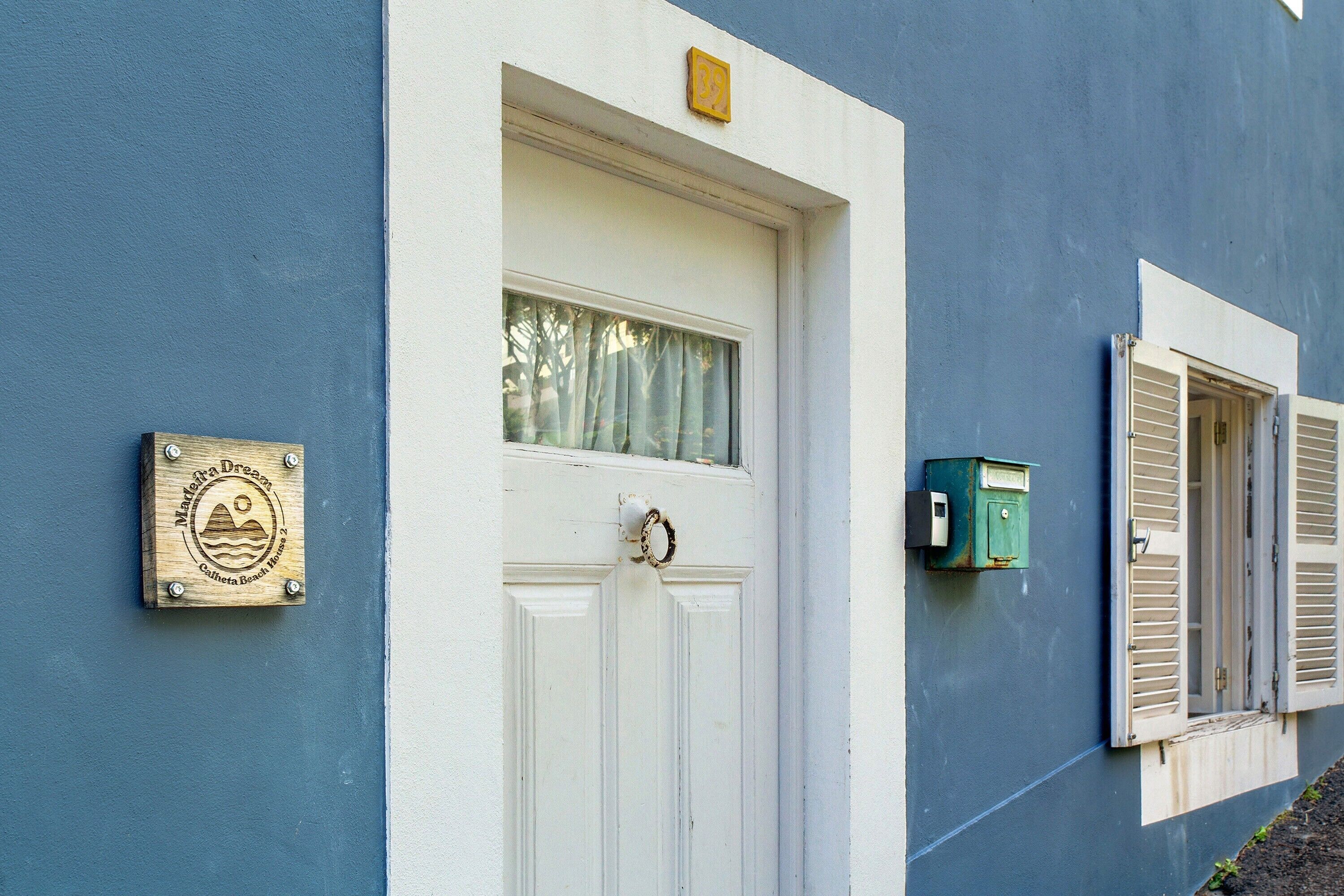 A white door with a window above it, a green mailbox, and a plaque on the wall.