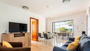 A modern living room with a TV, wooden entertainment unit, and a sofa with cushions. - Villa Bini Mestral by Villa Plus (Binibeca)