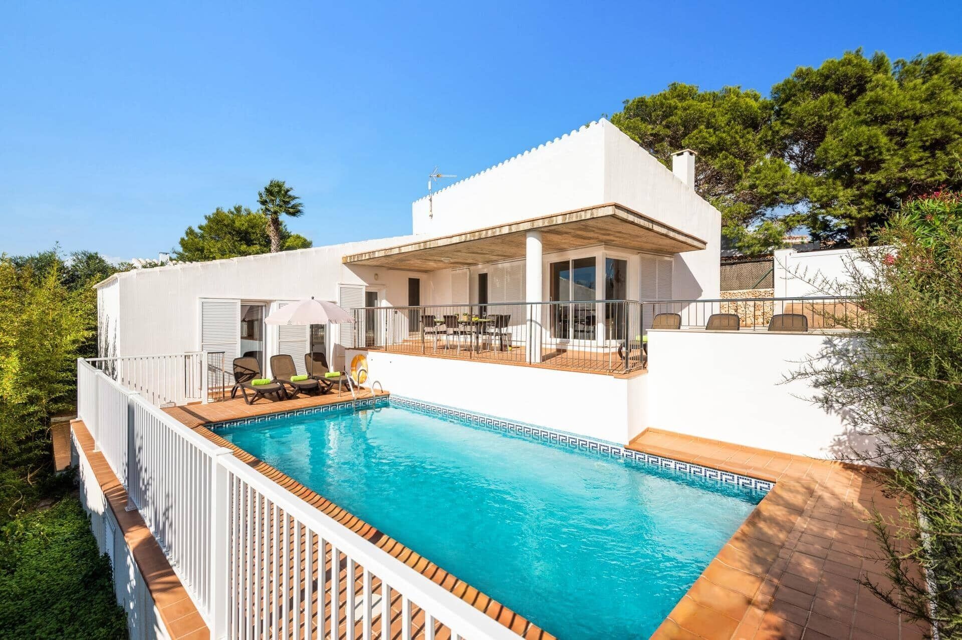 A modern villa with a swimming pool, outdoor seating, and a covered patio.