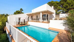 Een moderne villa met een zwembad, buitenmeubels en een overdekt terras.