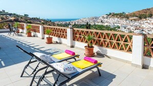 Una terrazza con lettini, piante in vaso e vista su una cittadina costiera.