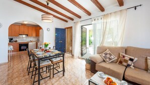 Un'ampia zona giorno con tavolo da pranzo, divano e cucina sullo sfondo.