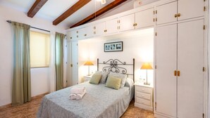 Una camera da letto con un letto, comodini, un armadio e un soffitto con travi a vista.