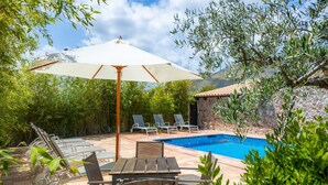 A poolside area with a table and chairs, a large umbrella, and a pool. - Villa 'Can Magraner' with Mountain View, Wi-Fi and Air Conditioning (Port de Pollensa)