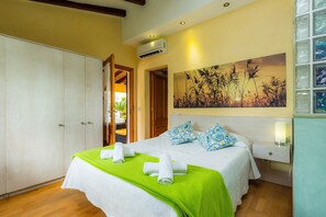 A hotel room with a bed, a wardrobe, an air conditioning unit, a painting on the wall, and a nightstand with a lamp. - Villa 'Can Magraner' with Mountain View, Wi-Fi and Air Conditioning (Port de Pollensa)