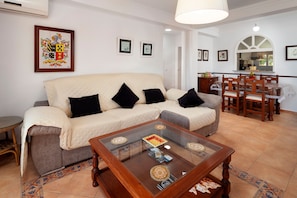 A living room with a sofa, a glass coffee table, a dining table with chairs, and a kitchen area in the background. - Apartment "Playa Rincón De La Victoria" with Sea View, Private Terrace & Wi-Fi (Rincón de la Victoria)