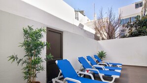 A terrace with lounge chairs and a potted plant.