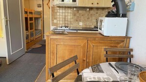 Een kleine keuken met houten kastjes, een magnetron en een koffiezetapparaat.