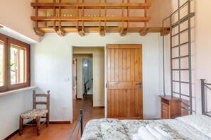 A bedroom with a bed, a wooden chair, a wardrobe, and a window.