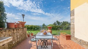 An outdoor patio with a table and chairs, potted plants, and a view of the landscape. - Apartment 'La Tavernetta' with Shared Pool, Private Terrace and Wi-Fi (Castelfranco Piandiscò)