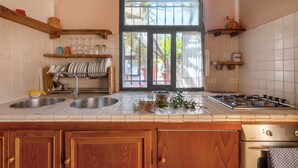 A kitchen with two sinks, a stove, and a window with a view of the outside. - Apartment 'La Tavernetta' with Shared Pool, Private Terrace and Wi-Fi (Castelfranco Piandiscò)