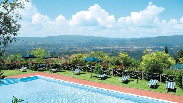 A swimming pool with lounge chairs and umbrellas, surrounded by greenery and a view of distant hills. - Apartment 'La Tavernetta' with Shared Pool, Private Terrace and Wi-Fi (Castelfranco Piandiscò)