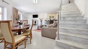 Un salon moderne avec un coin repas, un escalier et une cuisine en arrière-plan.