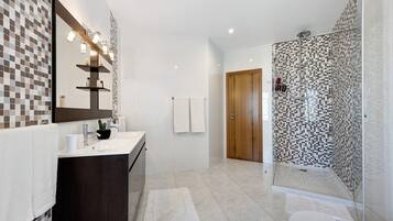 Ein modernes Badezimmer mit großem Spiegel, Waschbecken, Dusche und Toilette.
