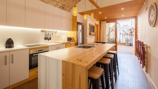 A modern kitchen with a wooden island, stainless steel appliances, and pendant lighting. - Sant Rafel House – Private Terrace, 5-Minute Walk to the Beach (ARENYS DE MAR)