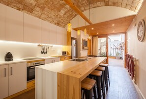 A modern kitchen with a wooden island, stainless steel appliances, and pendant lighting.