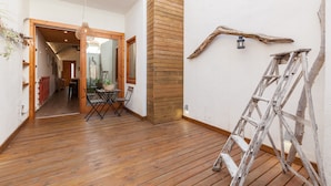 A wooden-floored interior with a dining area, a wooden column, and a ladder against the wall. - Sant Rafel House – Private Terrace, 5-Minute Walk to the Beach (ARENYS DE MAR)