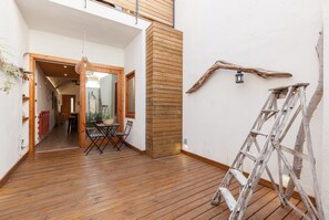 A wooden-floored interior with a dining area, a wooden column, and a ladder against the wall.