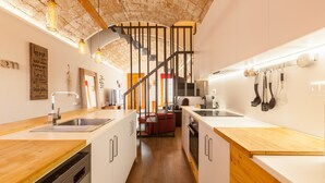 A modern kitchen with wooden countertops, stainless steel appliances, and a brick ceiling. - Sant Rafel House – Private Terrace, 5-Minute Walk to the Beach (ARENYS DE MAR)