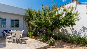 A patio with outdoor furniture, a white building, and a garden with various plants and a tree. - Villa "Tina" Close to the Beach and the City (torre lapillo)