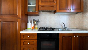 A kitchen with wooden cabinets, a gas stove, a dishwasher, and a sink. - Villa "Tina" Close to the Beach and the City (torre lapillo)