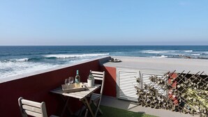 A balcony with a table, chairs, and a view of the ocean.