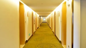 Pasillo de hotel con pisos alfombrados y puertas a ambos lados que dan a las habitaciones.