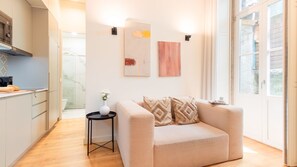 A modern living room with a beige sofa, a small side table with a vase, and artwork on the wall.