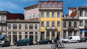 Una calle con edificios de colores, un ciclista y automóviles estacionados.