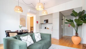Un salon moderne avec un canapé vert, deux lampes suspendues et une grande plante en pot.