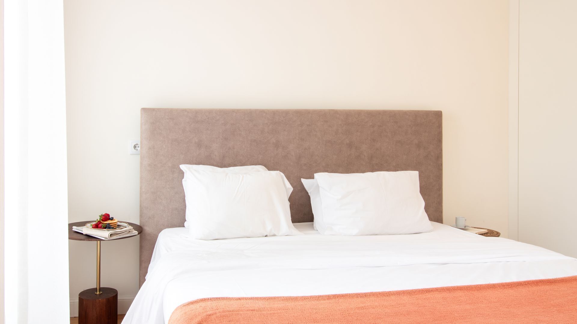 A neatly made bed with white bedding and a brown headboard in a hotel room.