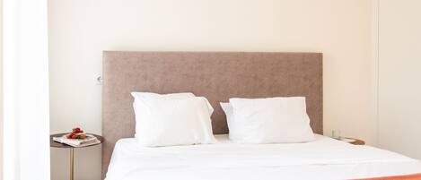 A neatly made bed with white bedding and a brown headboard in a hotel room.